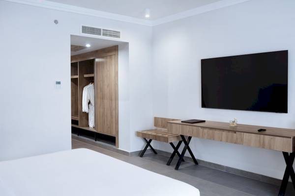 Ein modernes Hotelzimmer mit Fernseher, Schreibtisch und Kleiderschrank.