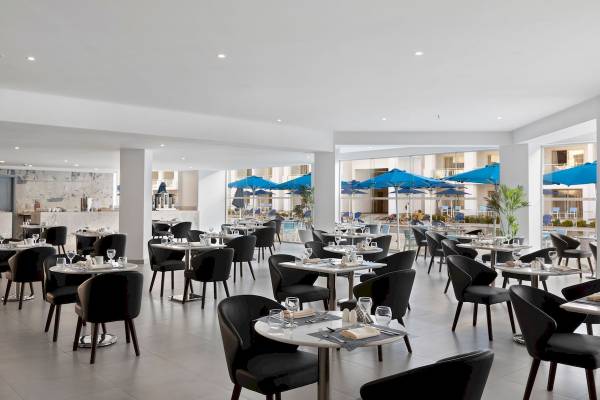 Innenansicht des Restaurants im Pickalbatros Blu Spa Resort mit blauen Sonnenschirmen und Tischen.
