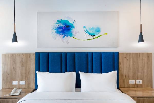 Hotelzimmer mit blauem Kopfteil, weißen Kissen, Telefon und blauer Blumentapete im Pickalbatros Blu Spa Resort.