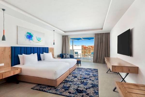 Innenansicht eines Hotelzimmers im Pickalbatros Blu Spa Resort mit zwei Betten, einem Balkon und moderner Einrichtung.