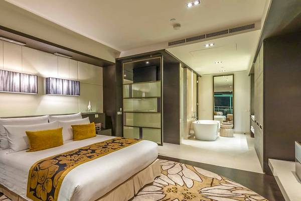 Schlafzimmer im Chatrium Hotel Riverside Bangkok mit Doppelbett, gelben Kissen und moderner Einrichtung.