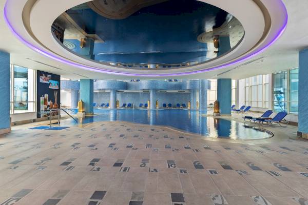 Innenpool des Pickalbatros Blu Spa Resorts mit blauen Wänden und Lounge-Stuhlreihen.