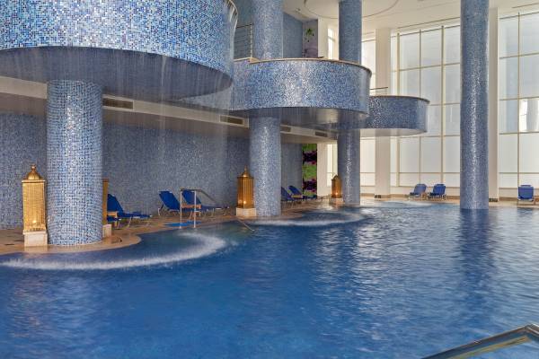 Innenpool des Pickalbatros Blu Spa Resorts mit blauen Säulen und Liegestühlen