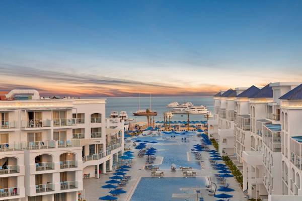 Außenansicht des Pickalbatros Blu Spa Resorts mit Swimmingpool und blauen Sonnenschirmen