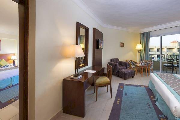 Ein elegantes Hotelzimmer im Amwaj Beach Club mit einem Schreibtisch, Stühlen und einem Bett.