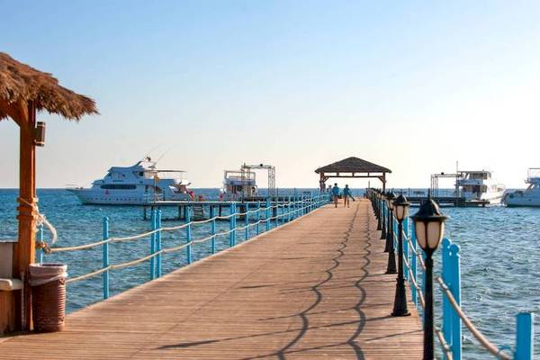 Holzsteg des Amwaj Beach Clubs mit Booten und Leuten, die spazieren gehen