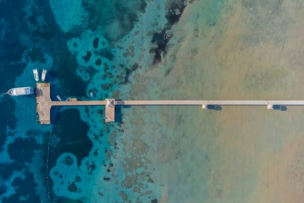 Luftaufnahme des Amwaj Beach Clubs mit Pier im Wasser und mehreren Booten