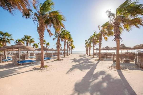Sonnenliegen und Palmen am Strand des Amwaj Beach Clubs