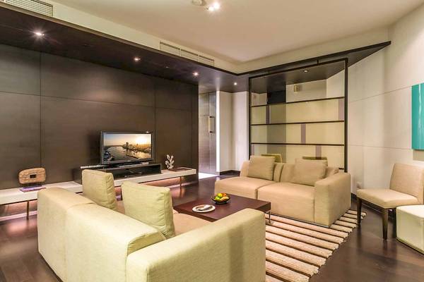 Wohnzimmer im Chatrium Hotel Riverside Bangkok mit Fernseher, Sofas und Kunstwerken an der Wand.