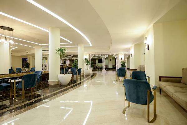 Lobby des Amwaj Beach Club Hotels mit weißen Marmorboden, goldenen Stühlen und Pflanzen.