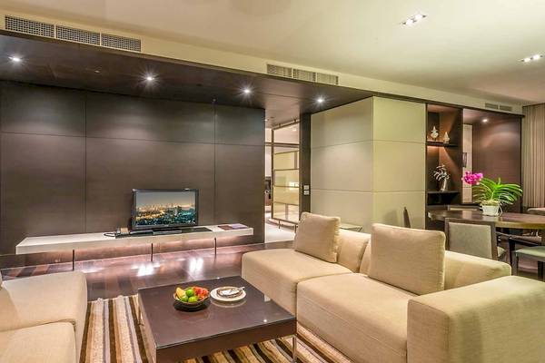 Das Wohnzimmer im Chatrium Hotel Riverside Bangkok mit modernen Möbeln und einem Fernseher.