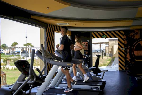 Mann und Frau, die auf Laufbändern im Fitnesscenter des Amwaj Beach Clubs trainieren.