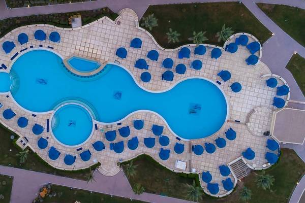 Oberflächenansicht des Amwaj Beach Club Pools mit blauen Sonnenschirmen und Wasser