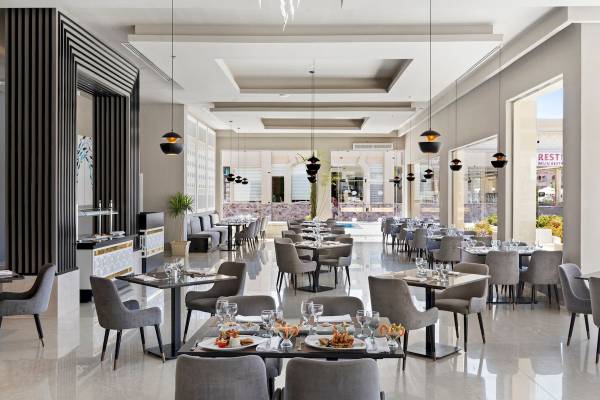 Innenansicht des Restaurants im Pickalbatros Aqua Vista Resort mit runden Tischen, Stühlen und Speisentellern.