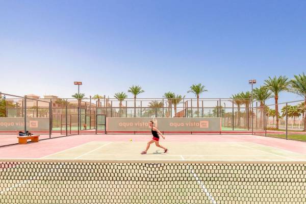 Tennisplatz im Pickalbatros Aqua Vista Resort mit einer Spielerin, die den Ball schlägt.