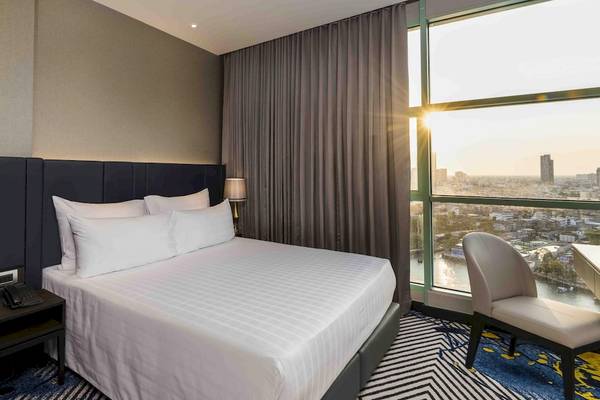 Hotelzimmer im Chatrium Hotel Riverside Bangkok mit Bett, Schreibtisch und Flussblick.