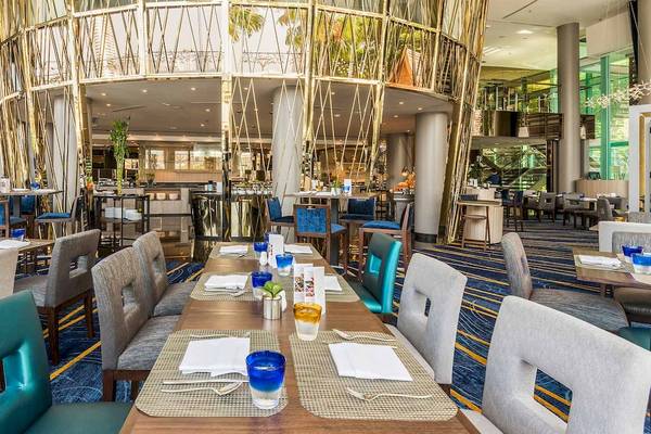 Restaurant-Innenbereich des Chatrium Hotel Riverside Bangkok mit langen Tischen, blauen Stühlen und einer zentralen goldenen Struktur.