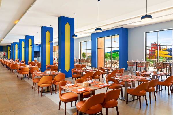 Restaurant im Pickalbatros Water Valley Resort by Neverland mit blauen und gelben Säulen und Tischen im Freien.