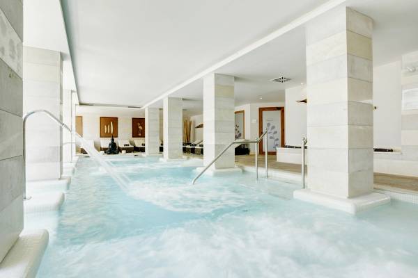 Innenansicht des Spa-Bereichs im Hotel Grupotel Los Principes mit einem großen Schwimmbecken und weißen Säulen.