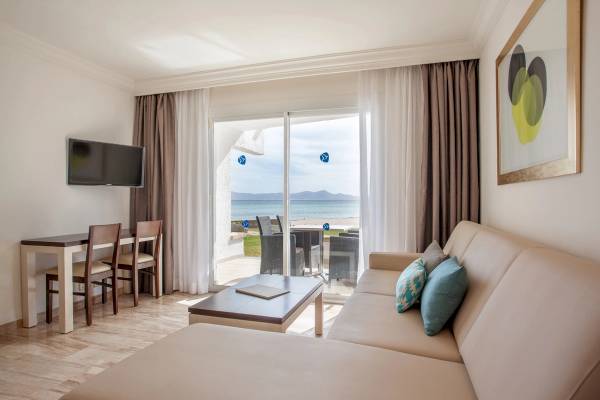 Wohnbereich im Hotel Grupotel Los Principes mit Blick auf das Meer und einem Fernseher an der Wand.