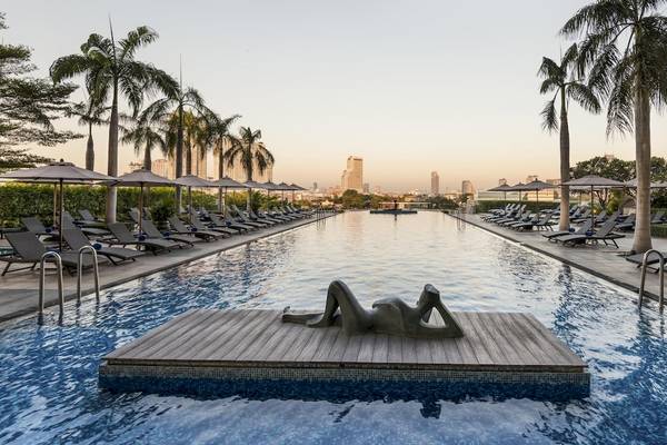Ein großer Swimmingpool mit Sonnenliegen und Sonnenschirmen im Chatrium Hotel Riverside Bangkok