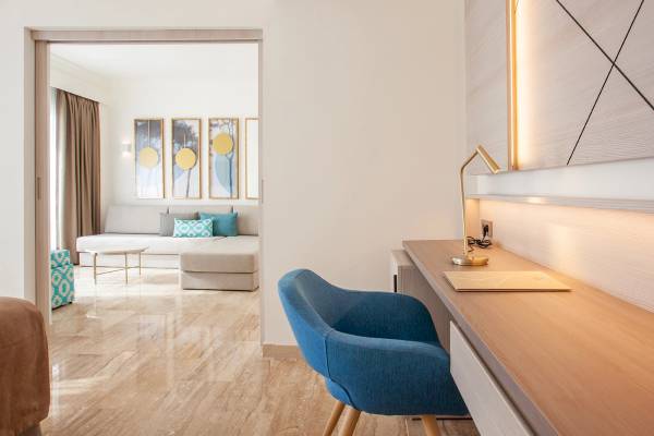 Inneneinrichtung des Grupotel Los Principes & Spa mit Schreibtisch, Stuhl und Wohnzimmer im Hintergrund.