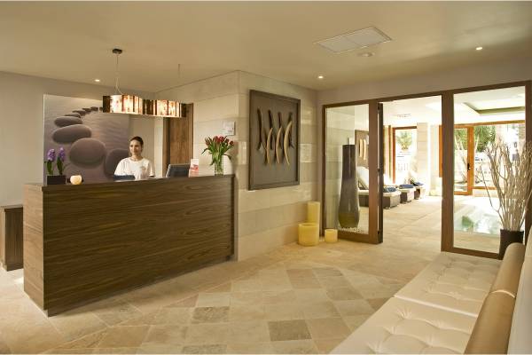 Empfangsbereich des Grupotel Los Principes & Spa mit Rezeptionistin, Blumen und Loungebereich