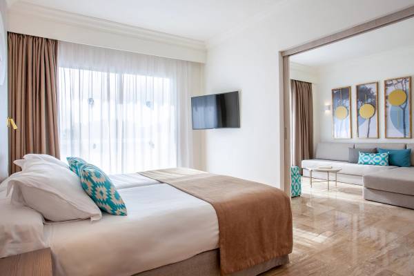 Hotelzimmer im Grupotel Los Principes & Spa mit zwei Betten, Fernseher und Wohnzimmerbereich.