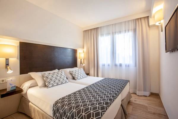 Hotelzimmer im Grupotel Los Principes & Spa mit zwei Betten, weißen Wänden und Holzboden.