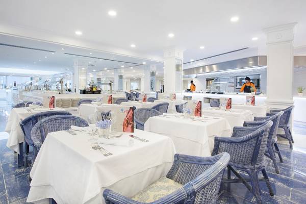 Restaurantbereich des Grupotel Los Principes mit blauen Stühlen und weißen Tischen.