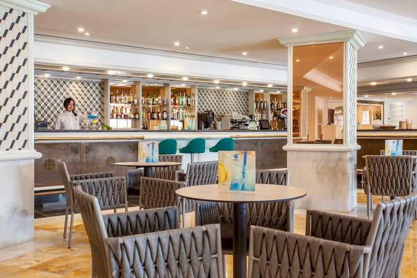 Barbereich im Grupotel Los Principes & Spa mit Kellnerin und gefüllten Regalen.