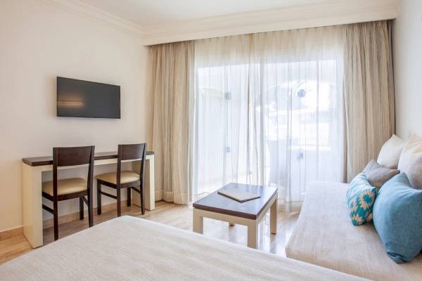 Innenansicht eines Hotelzimmers von Grupotel Los Principes & Spa mit einem Fernseher, Schreibtisch und zwei Stühlen.
