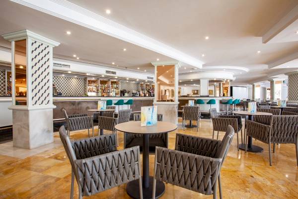Innenbereich des Grupotel Los Principes & Spa Hotels mit Bar, Tischen und Stühlen.