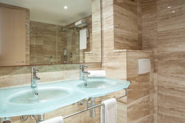 Doppelwaschbecken im Badezimmer des Grupotel Los Principes & Spa mit marmorierten Wänden und Handtüchern.