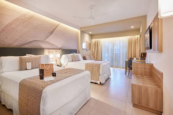 Doppelzimmer im RIU Palace Macao mit zwei Betten, einem Tisch, einem Fernseher und einer Wand mit einem großen Wandbild.