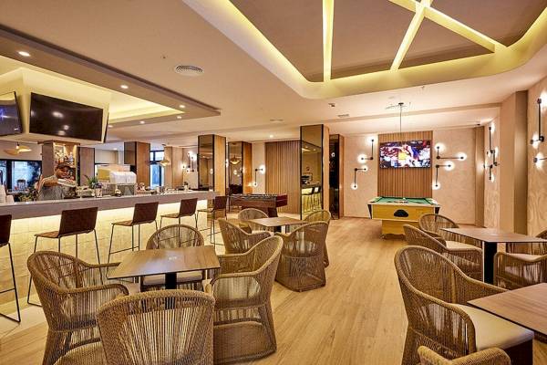 Innenansicht der Bar im RIU Palace Macao Hotel mit Barhockern, Tischen und Fernsehern.