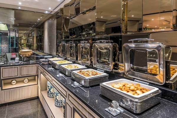 Speisenbereich im Chatrium Hotel Riverside Bangkok mit Edelstahlbuffets und Tellern.