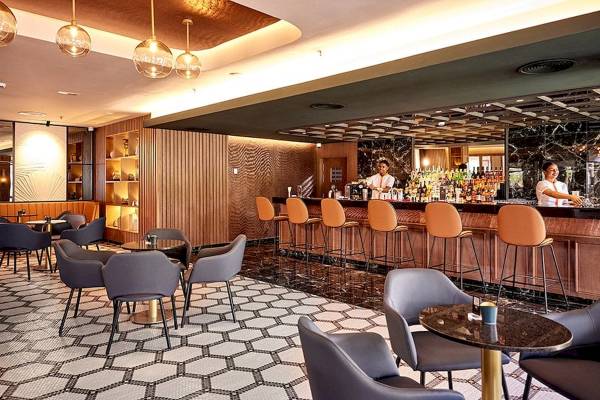 Innenansicht der Bar im RIU Palace Macao Hotel mit Barkeepern und gepolsterten Stühlen.