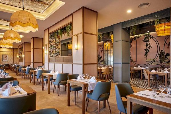 Innenansicht des Restaurants im RIU Palace Macao mit gedeckten Tischen und Stühlen, dekorativen Lampen und Pflanzen.