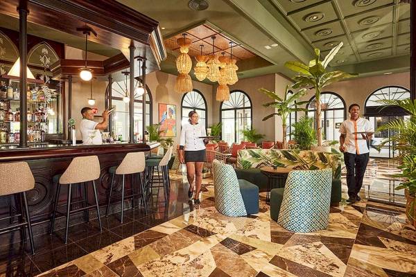 Lobby des RIU Palace Macao Hotels mit Bar, Gästen und tropischen Pflanzen.
