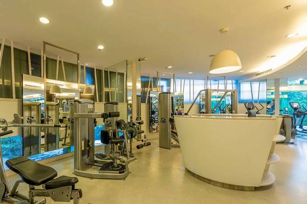 Fitnesscenter im Chatrium Hotel Riverside Bangkok mit verschiedenen Trainingsgeräten und einer Theke.