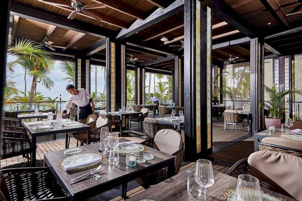 Das RIU Palace Macao Innenrestaurant mit Tischen, Stühlen und einem Kellner, der die Tische einrichtet.