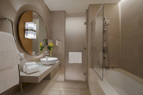 Badezimmer im Al Bandar Rotana Hotel mit Waschbecken, Spiegel und Badewanne.