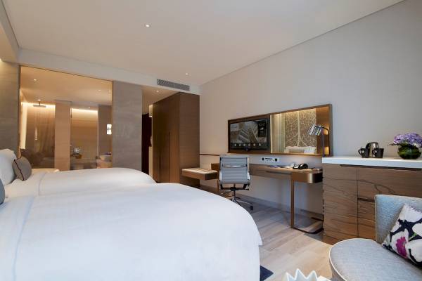Schlafzimmer im Al Bandar Rotana Hotel mit zwei Betten, Schreibtisch, Stuhl und Fernseher.