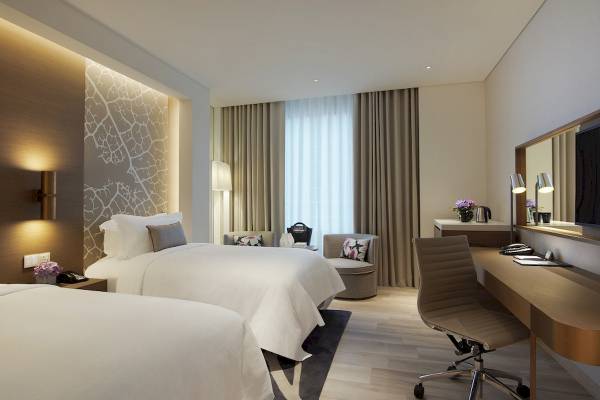 Zwei Betten in einem Hotelzimmer von Al Bandar Rotana, mit modernen Möbeln und Dekoration.