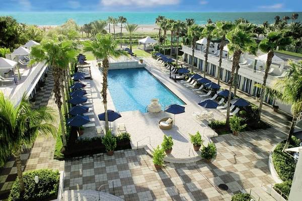 Luftaufnahme des Kimpton Surfcomber Hotels mit Swimmingpool, Sonnenliegen und Palmen.