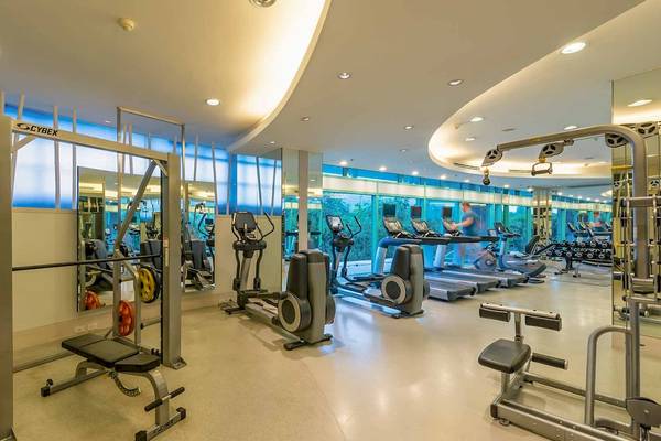 Fitnesscenter im Chatrium Hotel Riverside Bangkok mit modernen Geräten und großen Fenstern.