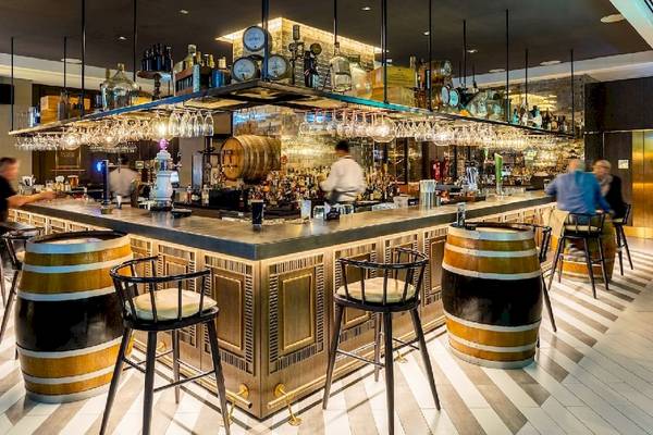 Bar im Al Bandar Rotana Hotel mit Holzfässern und Hockern.