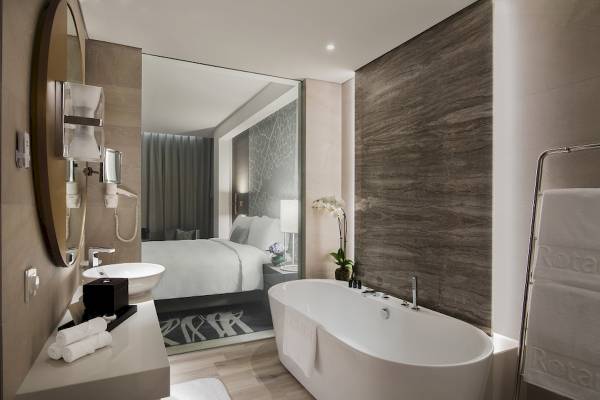 Badezimmer des Al Bandar Rotana Hotels mit Badewanne, Waschbecken und Spiegel.