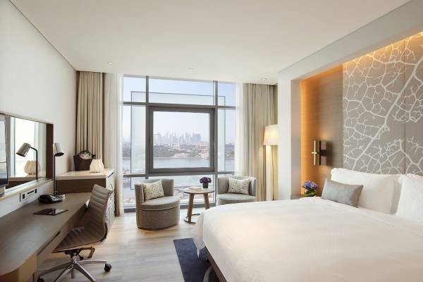 Innenansicht eines Schlafzimmers im Al Bandar Rotana Hotel mit Blick auf die Stadt.